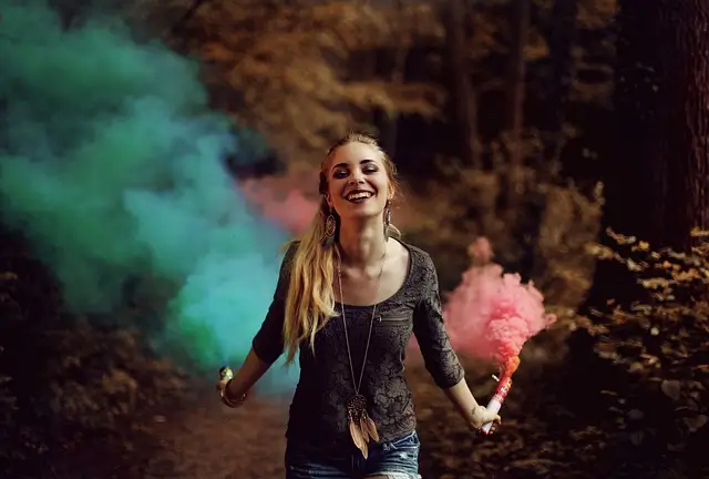 a debt-free woman holding pink and blue smoke bombs