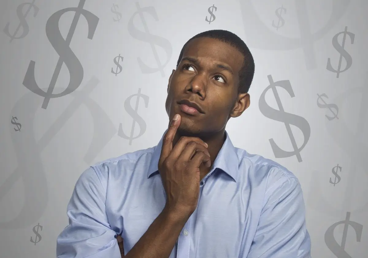 A thoughtful man with a blue shirt looking up, surrounded by floating dollar sign symbols, symbolizing financial contemplation.